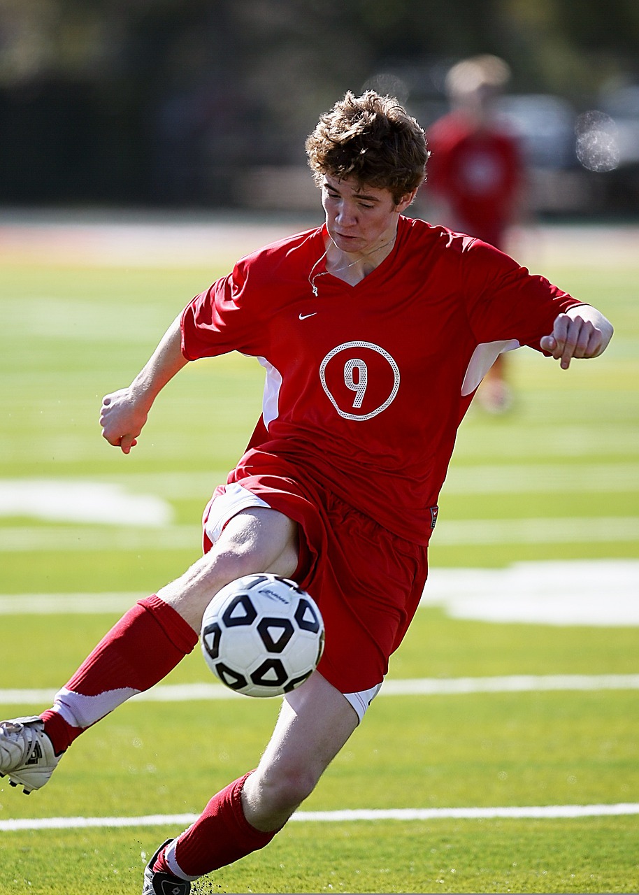 soccer player in red shirt with ball
